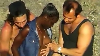 非洲裔美国女人在海洋边与两个白人男子享受三人行